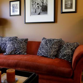 A cozy living room with a red sofa adorned with patterned cushions and framed wall art.