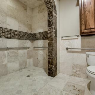 A modern bathroom featuring a tiled walk-in shower and toilet.