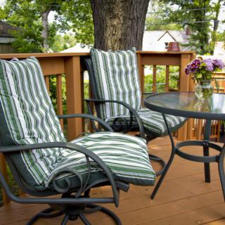 A cozy outdoor patio setup with cushioned chairs and a small table on a wooden deck.