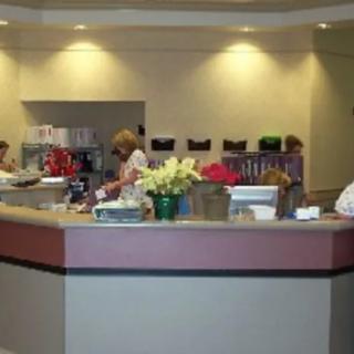 A reception area with people working behind the desk and flowers on the counter.