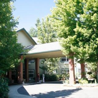 A building entrance surrounded by lush green trees on a sunny day.