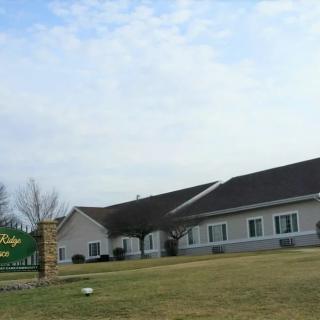 A church building with a sign and grassy area in front under a partly cloudy sky.