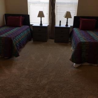 A neatly arranged bedroom with twin beds, lamps, and nightstands by the windows.