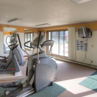 A small gym with elliptical machines and large windows providing natural light.