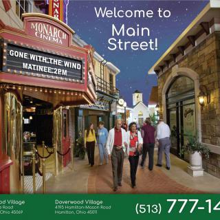 A promotional image showcasing a group of people walking down a themed indoor Main Street, with a cinema marquee and decorative lights creating an inviting atmosphere.