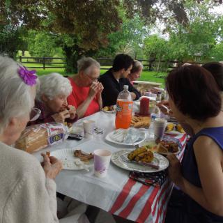A family enjoying a meal together at an outdoor picnic table.