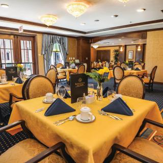 An elegant restaurant dining room with yellow tablecloths and neatly set tables.