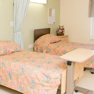 A view of a hospital room featuring two beds and a bedside table.