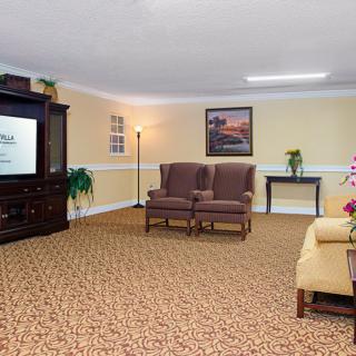 A cozy living room with armchairs, a sofa, television, and various decorations.