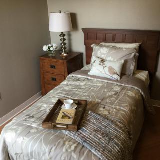 A cozy bedroom with a single bed, nightstand, and decorative tray.