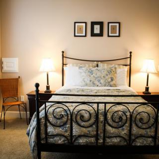 A cozy bedroom with a wrought iron bed frame, elegant bedding, and two bedside lamps.