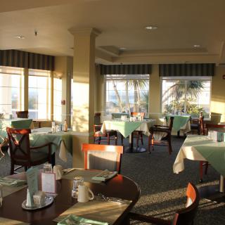 A brightly lit restaurant dining area with empty tables and chairs.