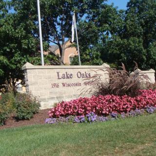 A welcome sign in Lake Oaks surrounded by vibrant flowers and greenery.