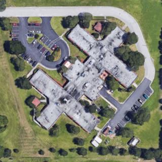 Aerial view of a complex featuring multiple wings and surrounded by landscaped areas.