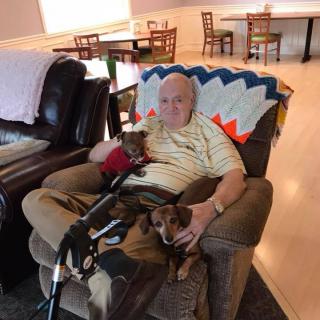 A man relaxing in a recliner with two dogs in a cozy living room.