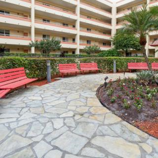 A courtyard with red benches and a stone pathway surrounded by greenery in an apartment complex.