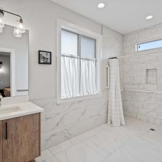 A modern bathroom with a spacious shower, wooden vanity, and elegant lighting.