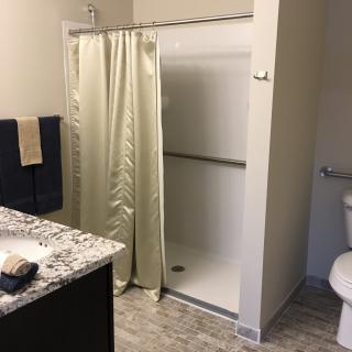A modern bathroom with a shower, toilet, and sink.