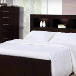 A modern bedroom with a dark wooden bed frame, white bedding, and a tall dresser.