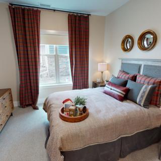 A cozy bedroom with elegant decor, featuring a neatly made bed, decorative pillows, and framed mirrors on the wall.