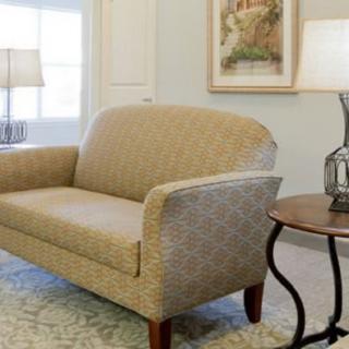 A cozy living room with a beige sofa, side table, and decorative lamp.