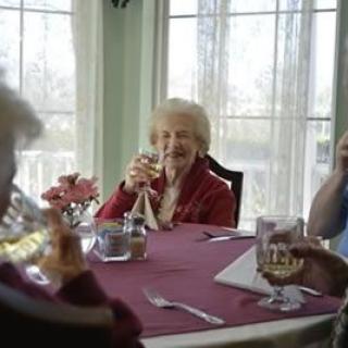 A joyful gathering of seniors sharing a meal and laughter at a dining table.