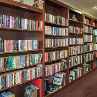 A library room with wooden bookshelves filled with various books.