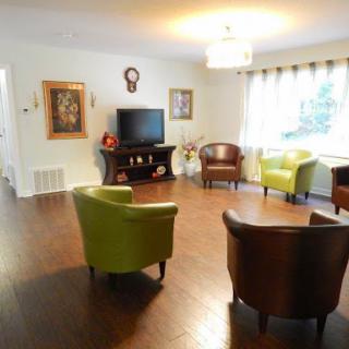 A cozy living room featuring colorful chairs, a television, and decorative artwork.