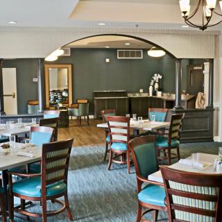 A modern restaurant interior featuring a cozy dining area with neatly arranged tables and chairs.