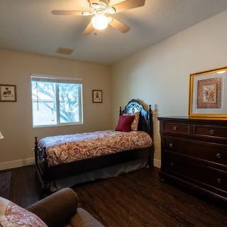 Cozy bedroom with two beds, a dresser, and wall art, illuminated by natural light from the window.