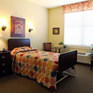 A cozy and colorful bedroom showcasing a single bed with a vibrant quilt, complemented by soft lighting and decorative elements.