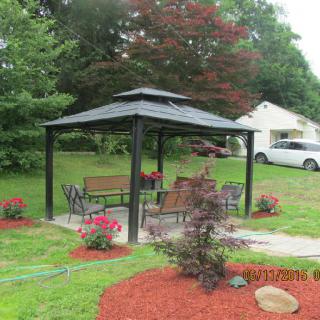 A charming gazebo with outdoor seating surrounded by a well-maintained garden.