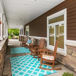 A cozy covered porch with rocking chairs and patterned rugs.