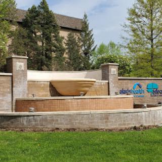 A serene outdoor fountain surrounded by lush greenery and architectural elements.