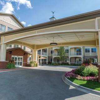 A well-landscaped building entrance with a covered driveway and flower beds.