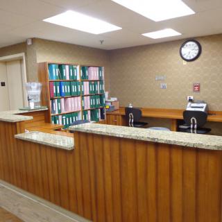 A tidy reception area with a wooden desk and shelves filled with files.