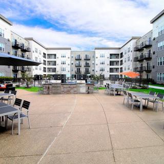 A modern apartment complex featuring a spacious courtyard with outdoor seating and amenities.