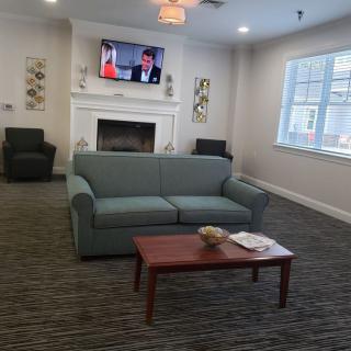 A cozy living room with a sofa, coffee table, and a television mounted above a fireplace.