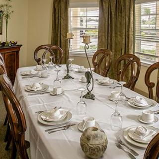 An elegantly set dining table with formal place settings and decorative candlesticks.