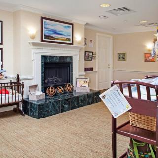 A cozy nursery room featuring a fireplace, crib, and artwork on the walls.