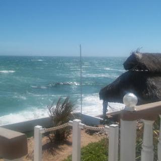 A scenic view of the ocean with waves crashing against the shore under a clear blue sky.