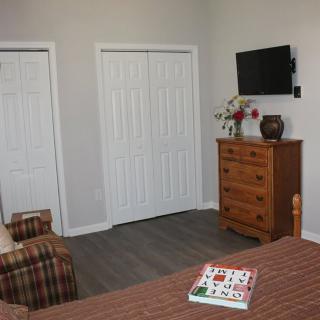 A cozy bedroom featuring a dresser, wall-mounted television, and closet doors.