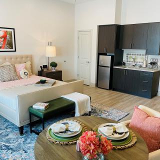 A modern studio apartment featuring an open layout with a cozy bed, compact kitchen, and a small dining area.