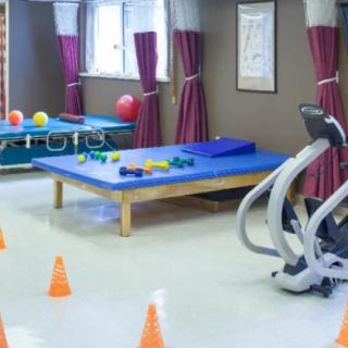 An indoor rehabilitation center equipped with therapy mats, exercise machines, and training cones.