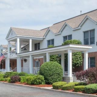 A residential building with a neatly landscaped front yard and a covered porch.