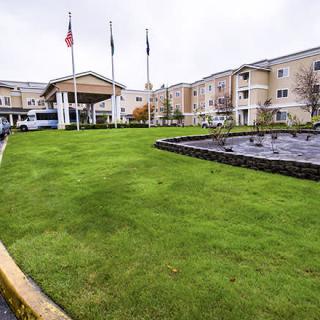 A hotel building with a manicured lawn and multiple flags at the entrance.