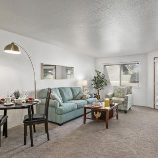 A cozy living room with a sofa, dining area, and a stylish lamp.
