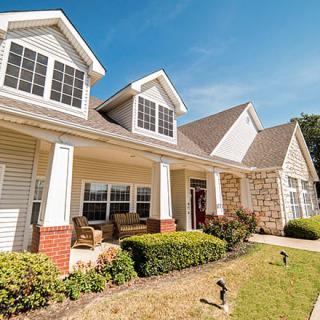 A suburban house with a well-maintained front porch and yard on a sunny day.