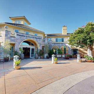 A sunny view of a large, elegant building with an arched entrance and well-maintained surroundings.