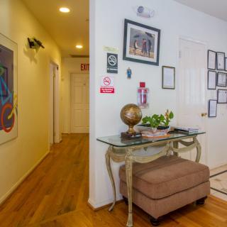 A welcoming hallway with wooden floors, adorned with artwork and a decorative table featuring a globe and plants.